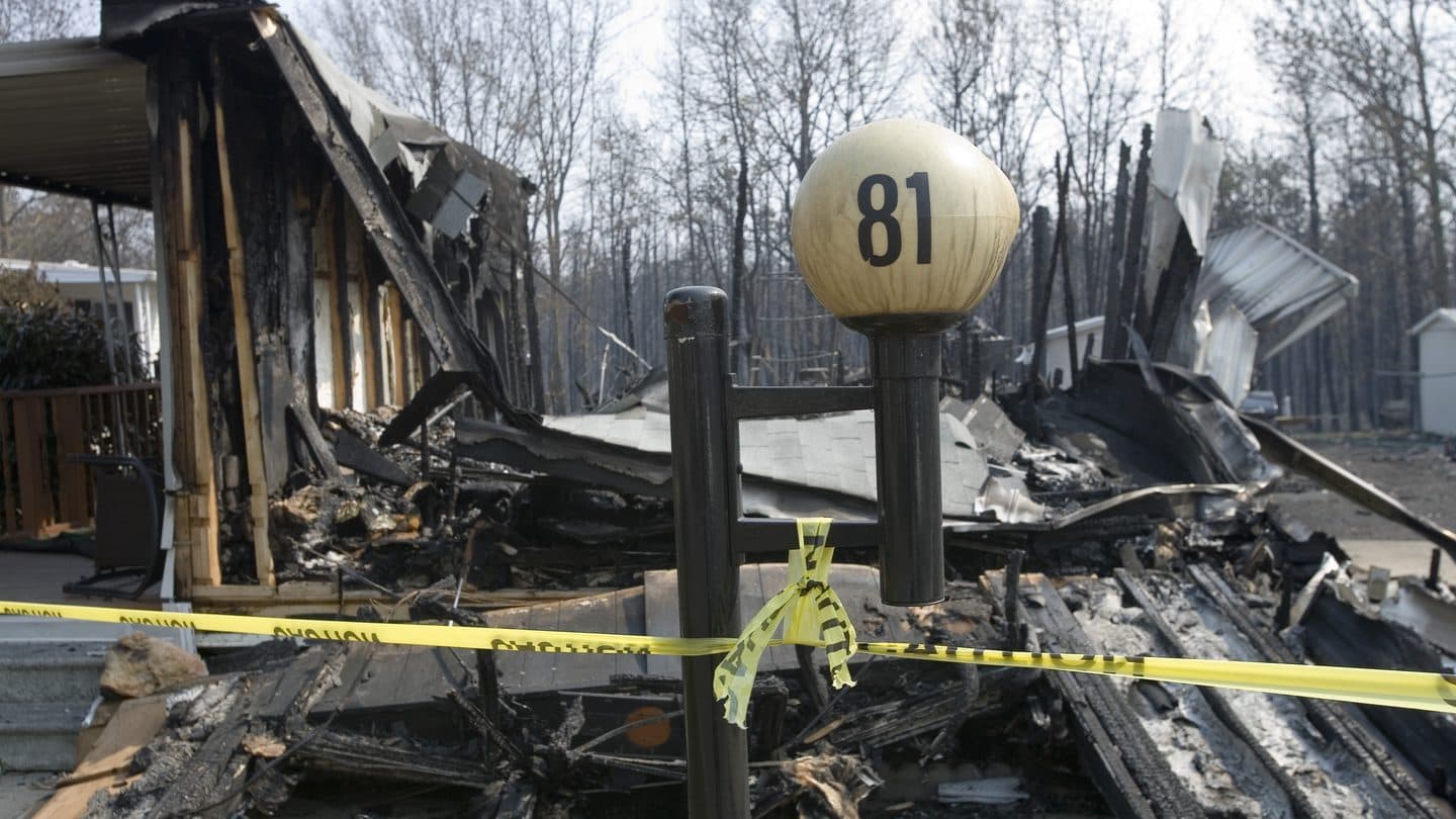 Burned house remains behind yellow caution tape after a residential fire
