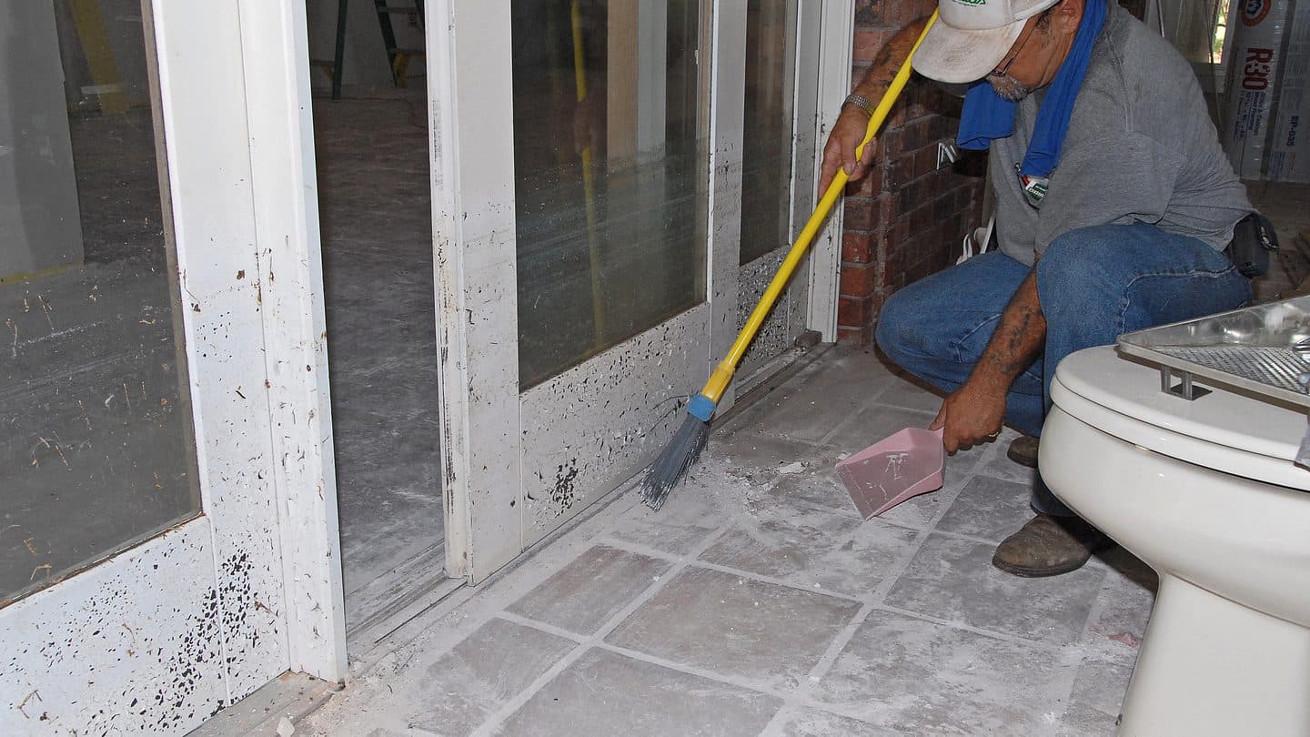 Mud and flood residue being swept from a tiled room after floodwaters receded