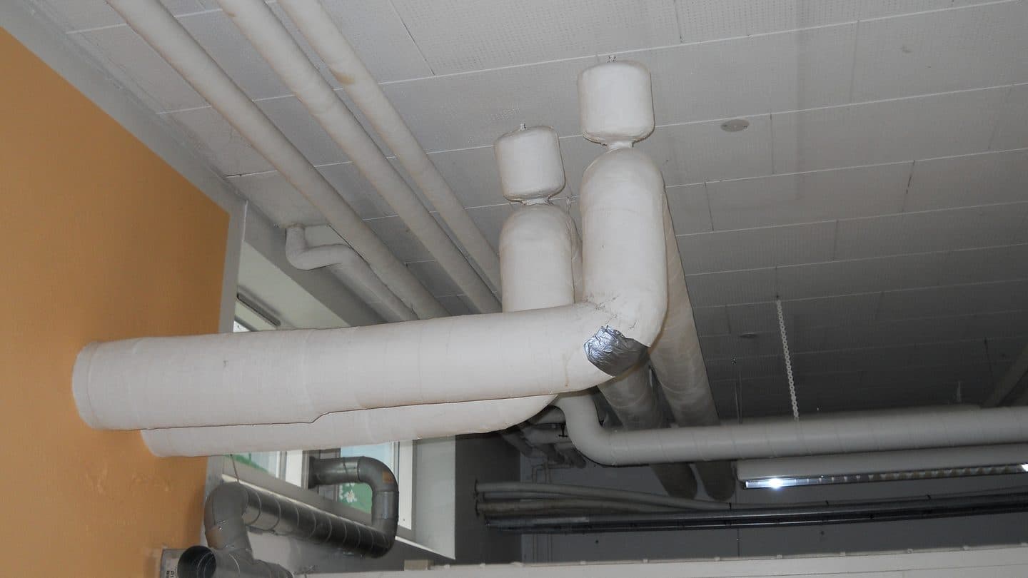 Asbestos insulation wrapped around heating pipes in a basement