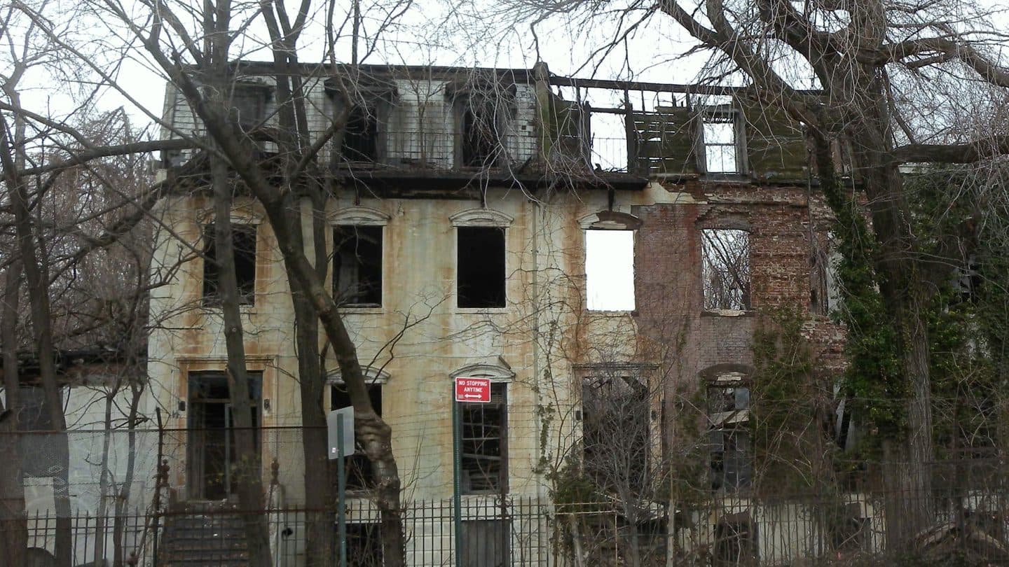 Decayed row house with empty windows, missing facade, and a damaged roof